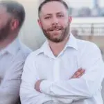 A man with his arms crossed wearing a white shirt.