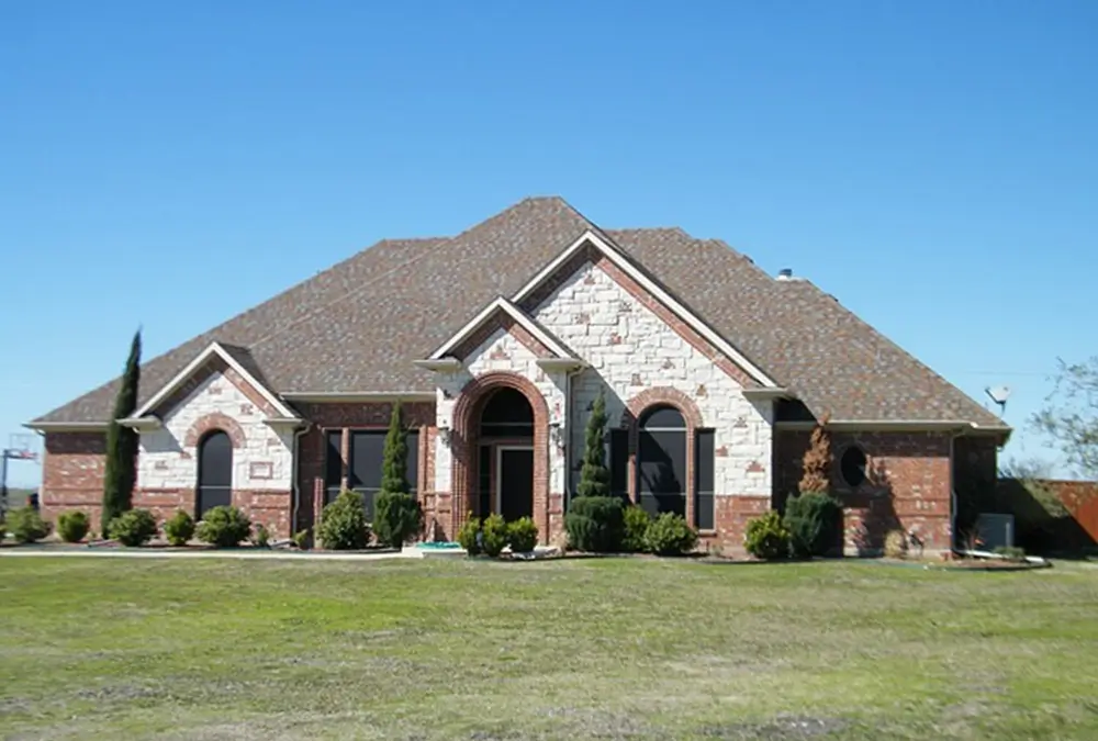 A large brick house with a green lawn.