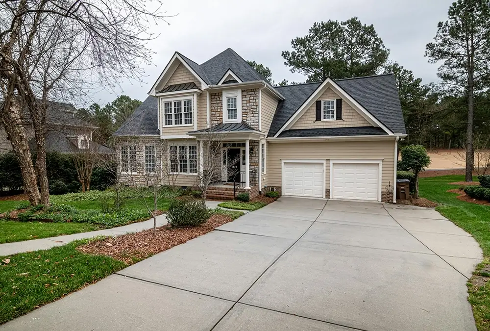 A large house with two garage doors and a driveway.