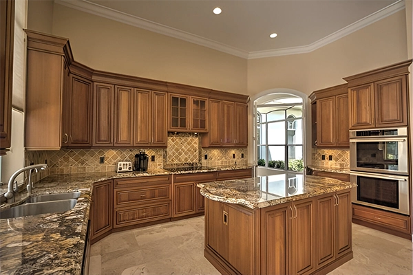 A kitchen with wooden cabinets and marble counter tops.