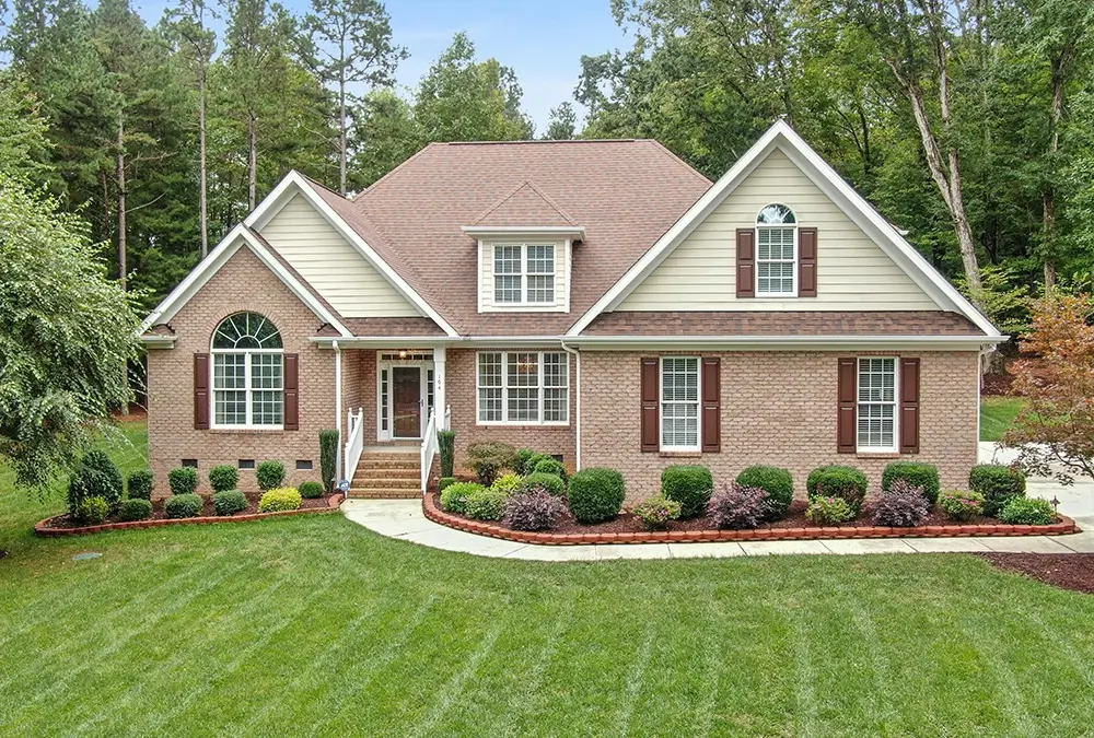 A large brick house with red shutters and white trim.