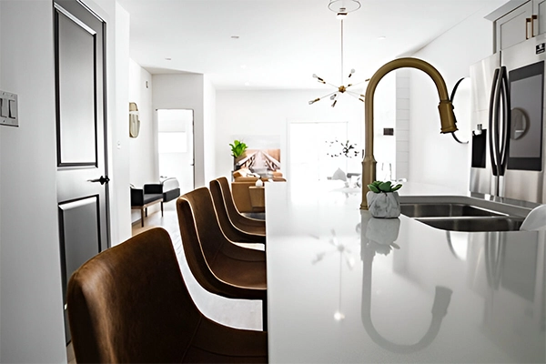 A kitchen with white counters and brown chairs.