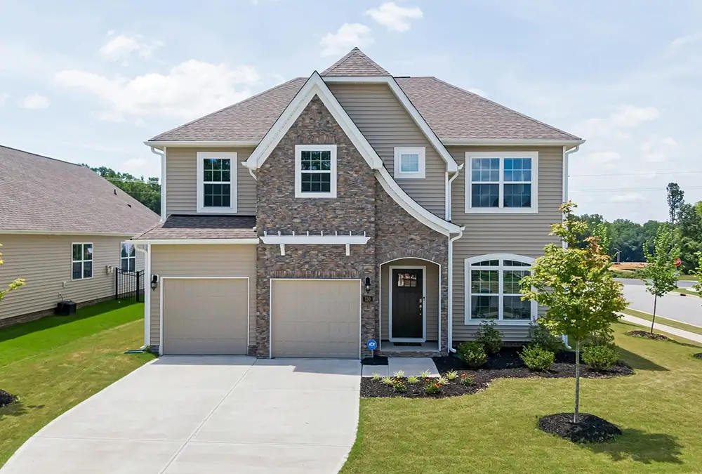 A large house with two garage doors and a driveway.