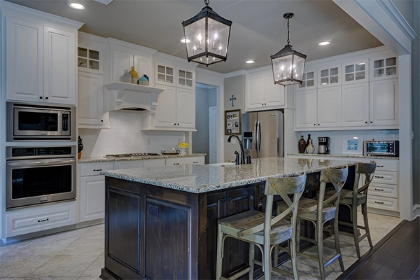 A kitchen with white cabinets and black island.