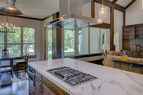 A kitchen with a stove and some chairs