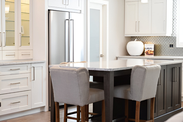 A kitchen with white cabinets and gray chairs.