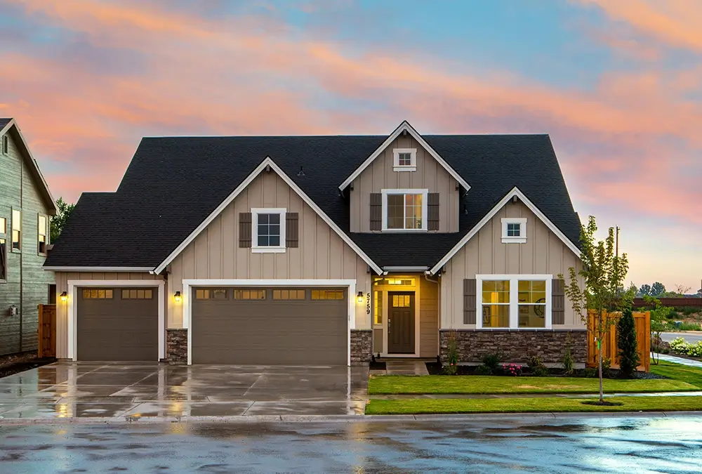 A house with a garage and water in front of it.