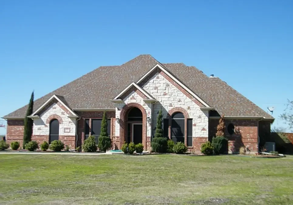 A large brick house with a green lawn.